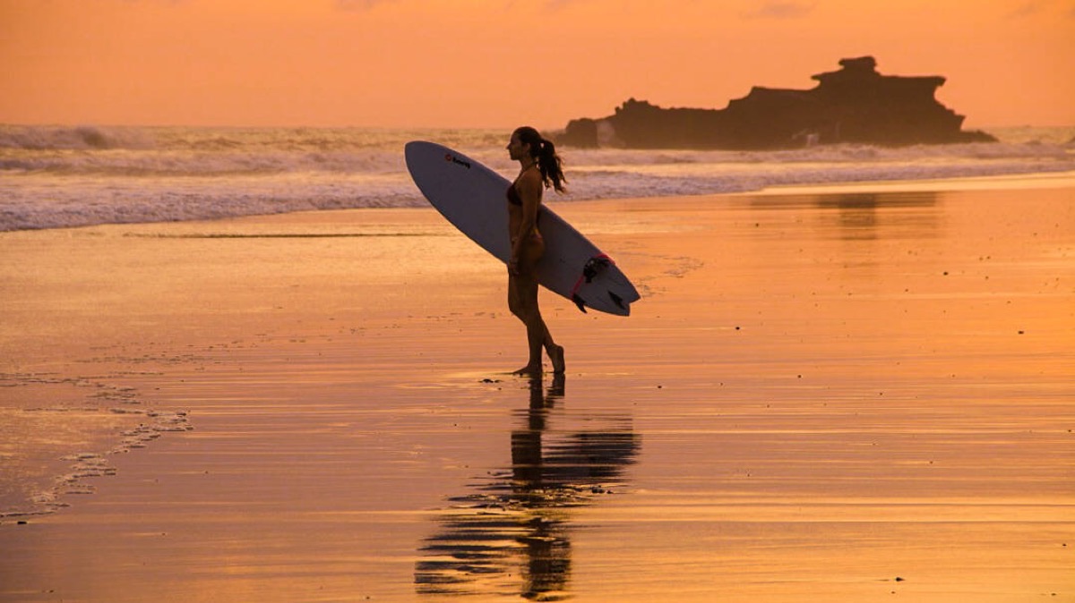 Surfer silhouette on Canggu beach at golden hour, Bali