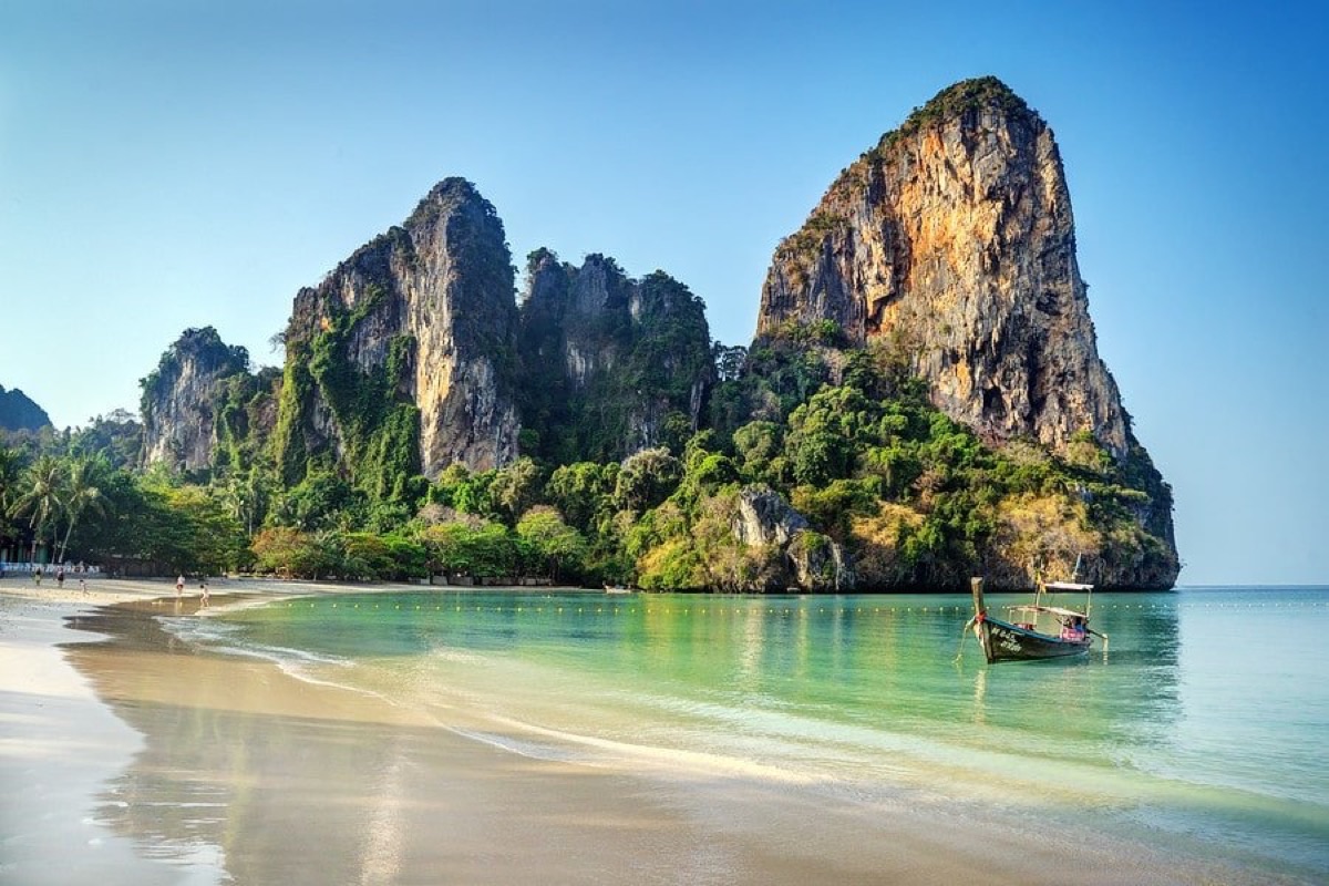 Railay Beach Krabi Thailand longtail boat on turquoise water with dramatic limestone cliffs