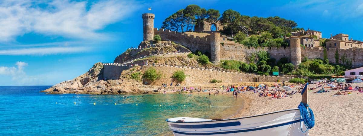 Tossa de Mar castle and beach on the Costa Brava with fishing boat and turquoise water