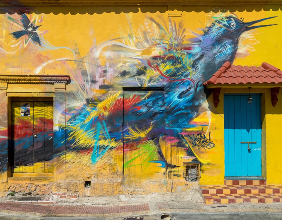 Vibrant colorful bird mural on a yellow colonial wall in Getsemani neighborhood, Cartagena, Colombia