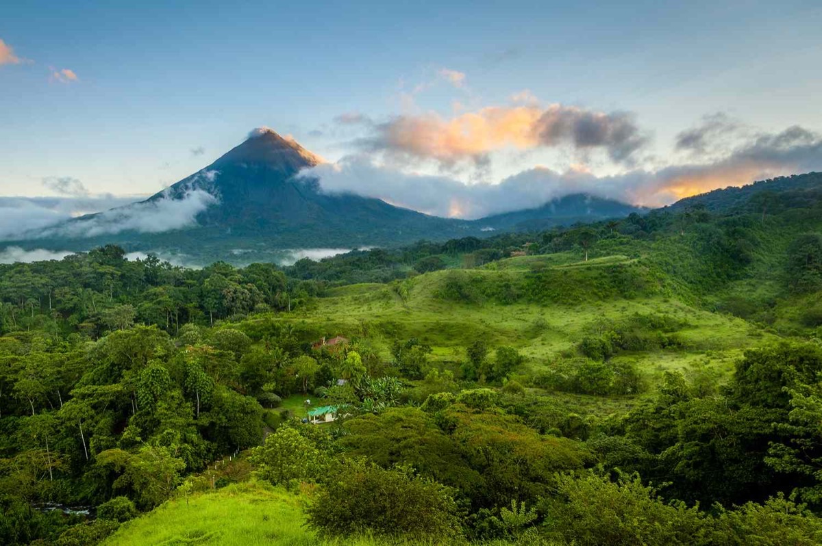 Arenal Volcano rising above lush green Costa Rica landscape in golden hour light