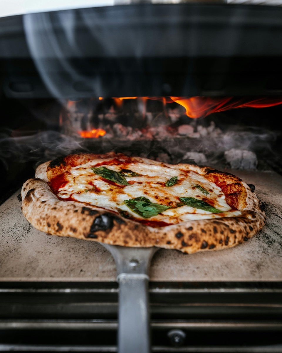 Authentic Neapolitan margherita pizza with charred crust fresh from a wood-fired oven