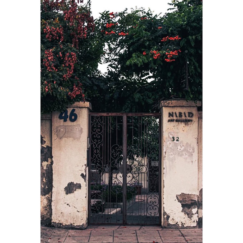 Charming entrance of Nabad Art Gallery with ornate iron gate and flowering tree in Jabal Lweibdeh