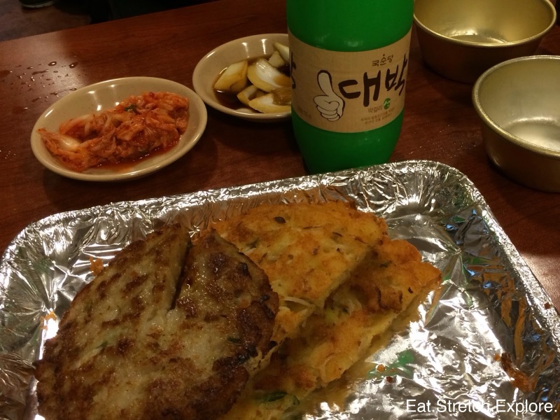 Bindaetteok mung bean pancake frying on a griddle at Gwangjang Market